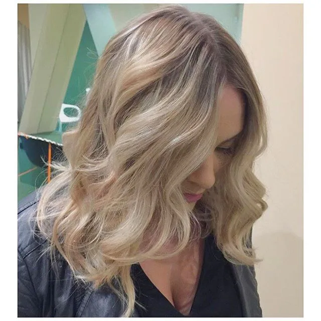 Warm-blonde soft waves against a mint salon wall
