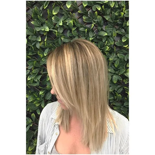 Soft-blonde lob against a green foliage wall